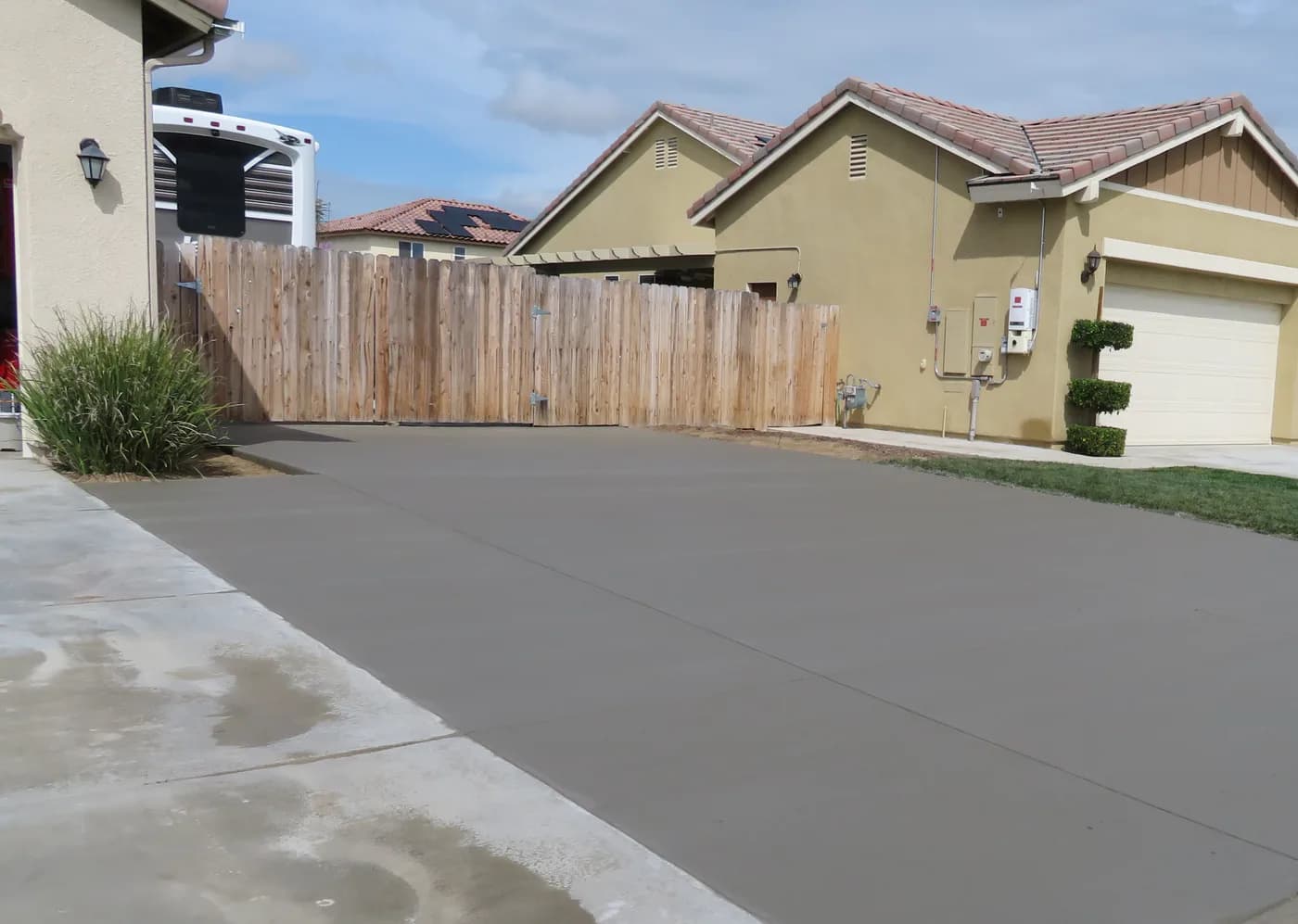 Freshly poured concrete driveway leading to a wood gate