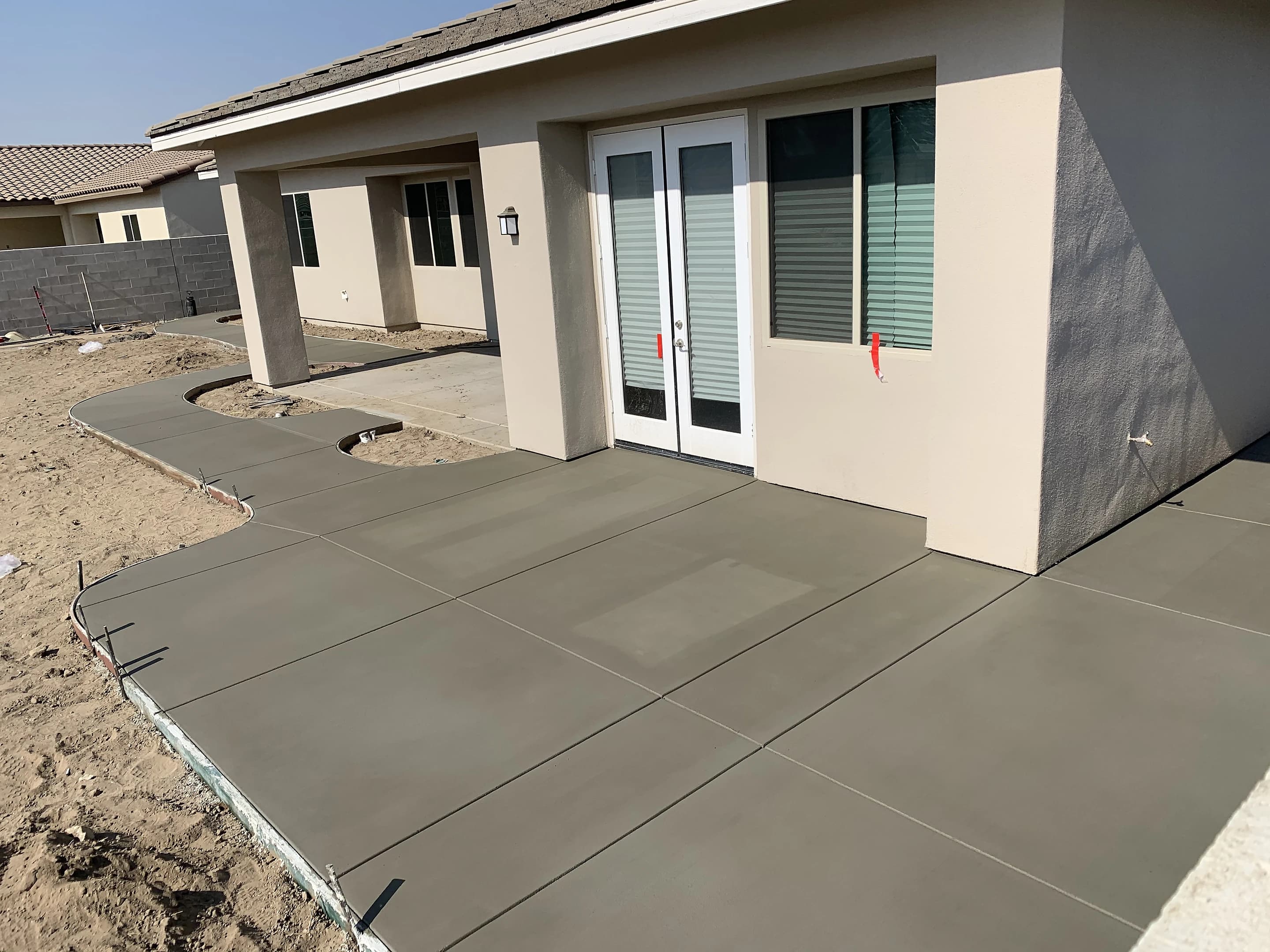 New concrete patio poured behind a newly built home, the yard still bare dirt