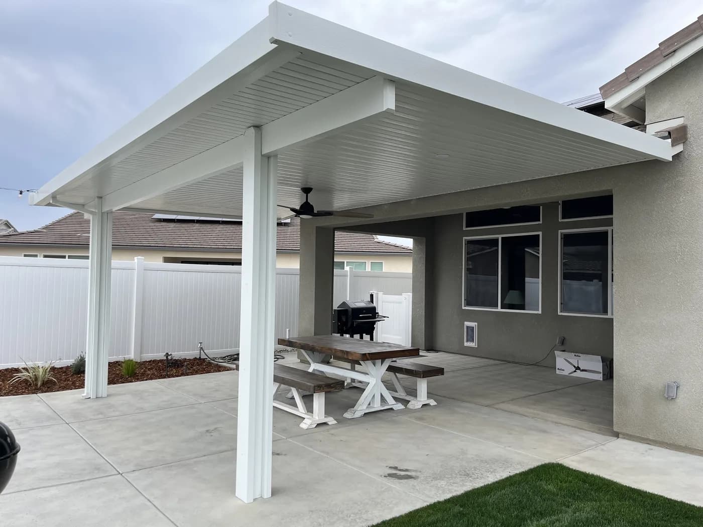 Concrete patio under a white patio cover with a picnic table