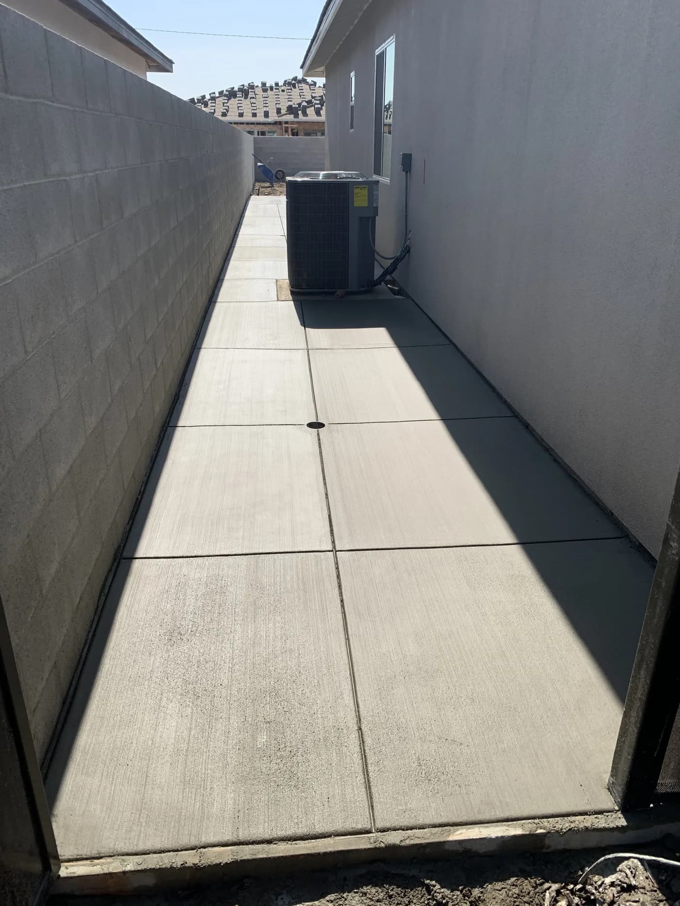 Concrete walkway down a side yard between a house and a block wall