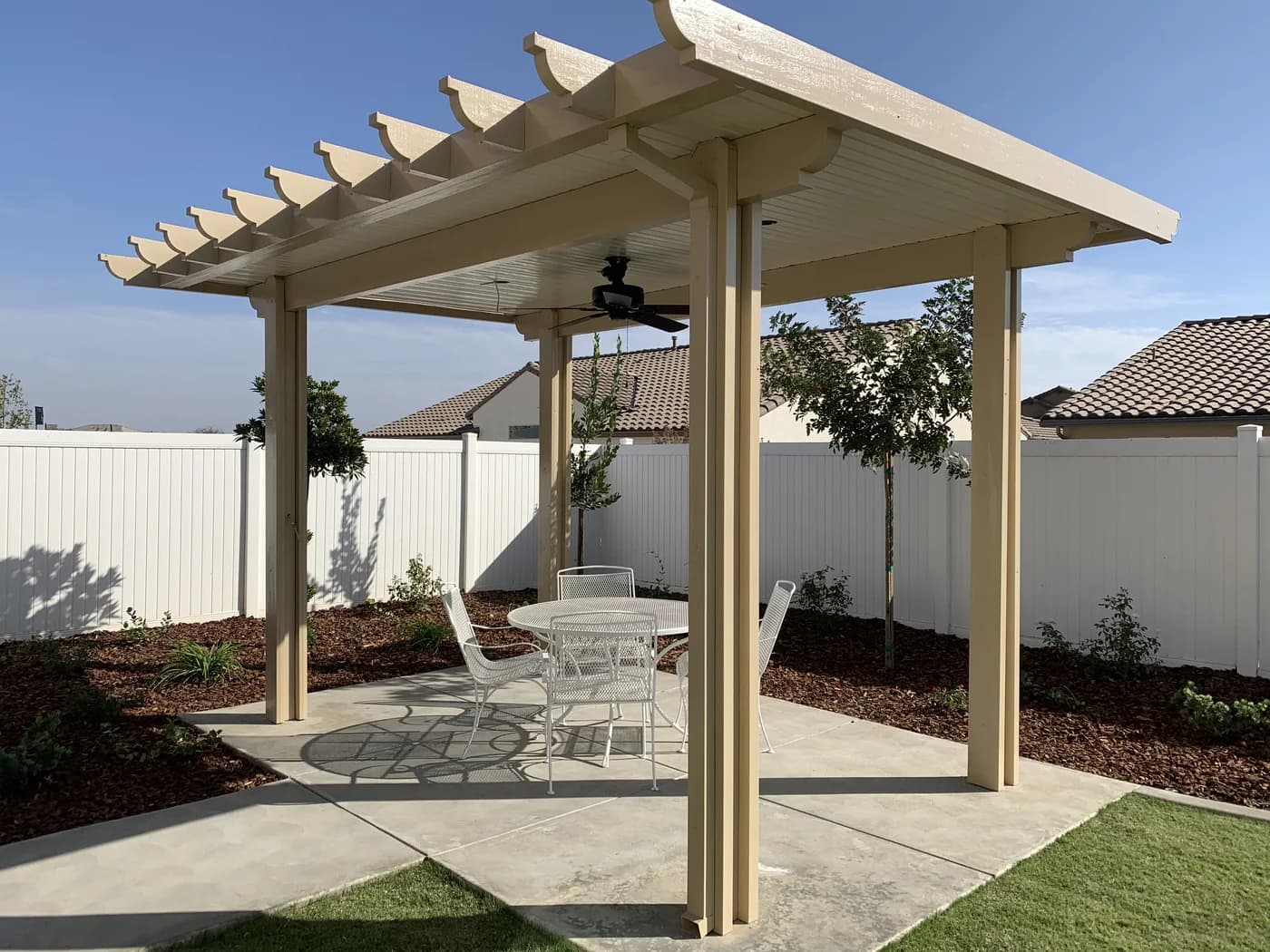 Cream freestanding patio cover with a ceiling fan over a round patio table