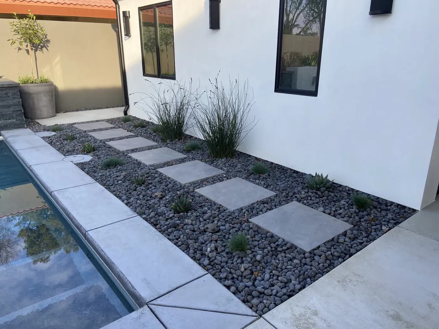 Gravel bed with grasses and agaves beside a pool
